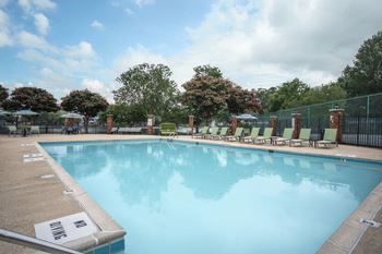 A large swimming pool surrounded by a fence and lounge chairs